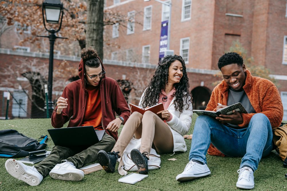 Três jovens conversando e sorrindo em um espaço ao ar livre